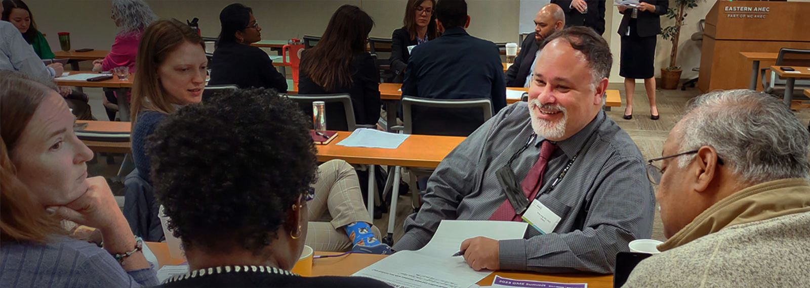 Photo of a group of people sitting around a table interacting with one another at an education program being held at Eastern AHEC